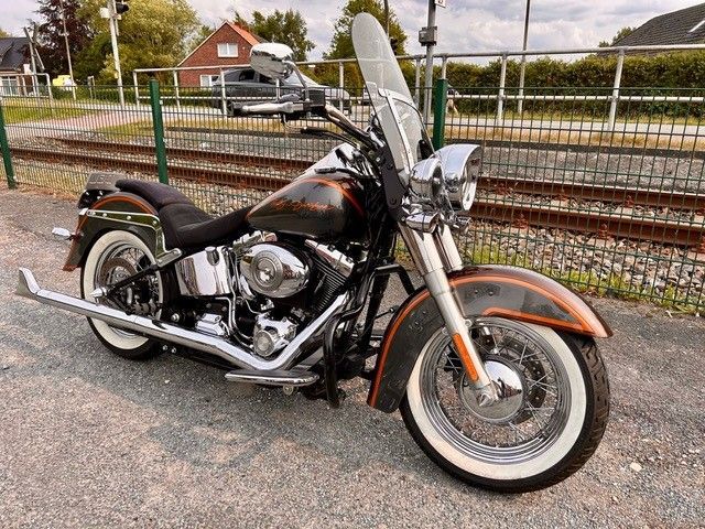 Ein Motorrad der Marke Harley Davidson ist am Straßenrand neben den Bahngleisen geparkt.