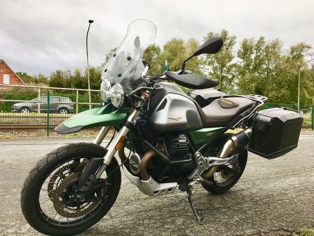 Am Straßenrand parkt ein grün-silbernes Motorrad.