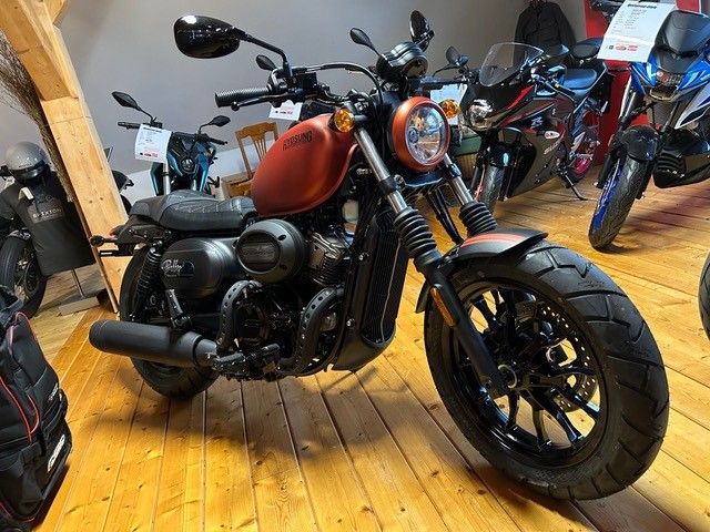 In einem Ausstellungsraum ist ein Motorrad auf einem Holzboden geparkt.