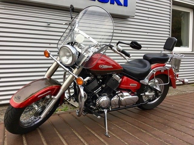 Vor einem Gebäude parkt ein rotes Motorrad mit Windschutzscheibe.