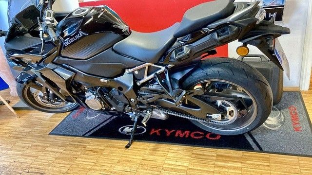 Schwarzes Sportmotorrad auf einer KYMCO-Fußmatte geparkt.