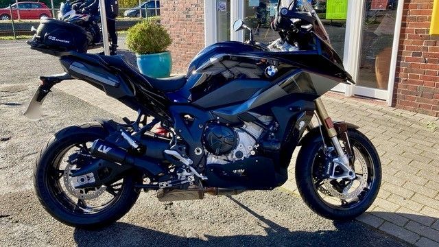 Schwarzes Motorrad BMW S1000 XR, geparkt auf einem gepflasterten Platz vor einem Gebäude.