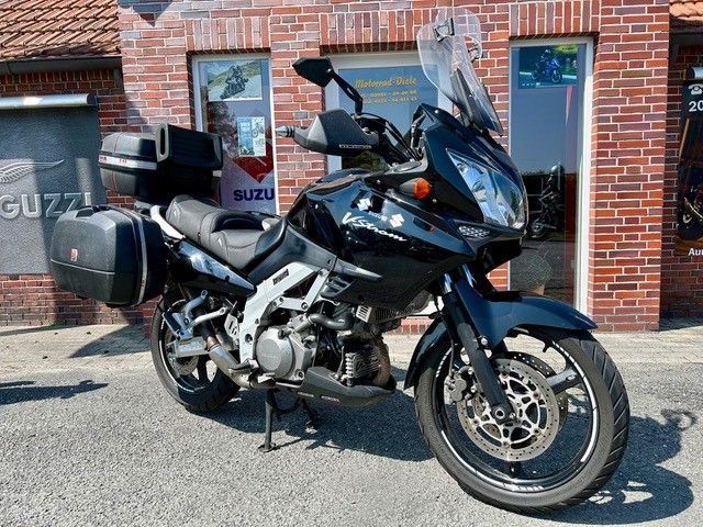 Vor einem Backsteingebäude parkt ein schwarzes Motorrad.