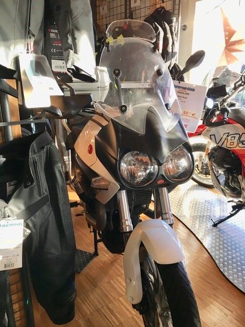 Ein schwarz-weißes Motorrad steht in einem Ausstellungsraum
