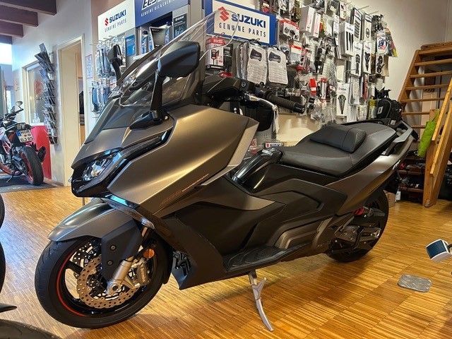 Ein Motorroller steht in einem Ausstellungsraum neben einer Treppe.