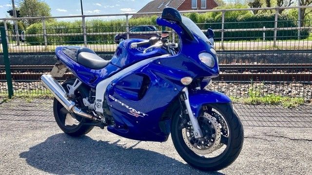Ein blaues Motorrad ist am Straßenrand geparkt.