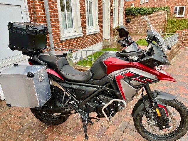 Ein rot-silbernes Motorrad steht vor einem Backsteingebäude