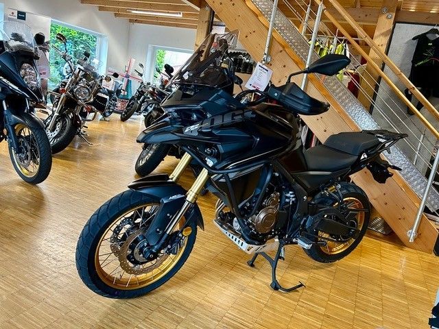 Ein schwarzes Motorrad steht auf einem Holzboden in einem Ausstellungsraum.