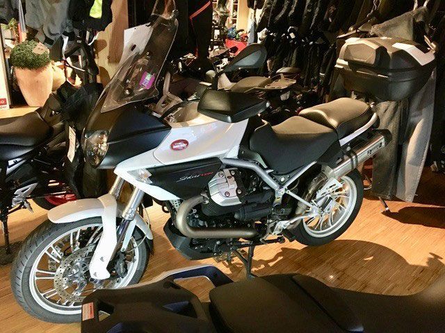 Ein schwarz-weißes Motorrad ist auf einem Holzboden geparkt
