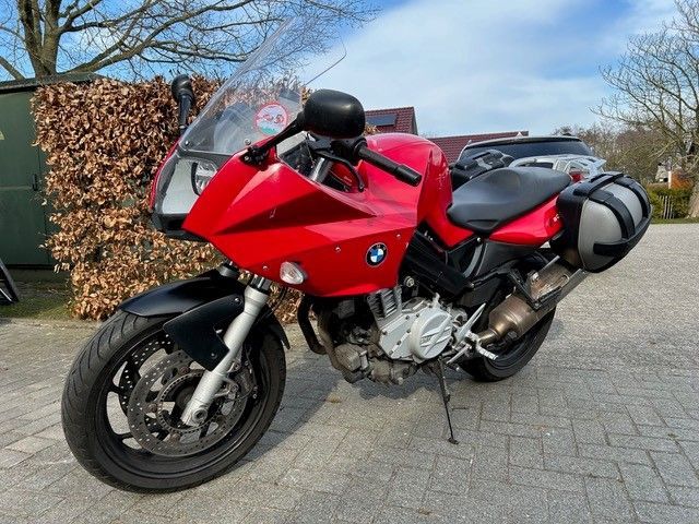Ein rotes BMW-Motorrad steht auf einem Parkplatz