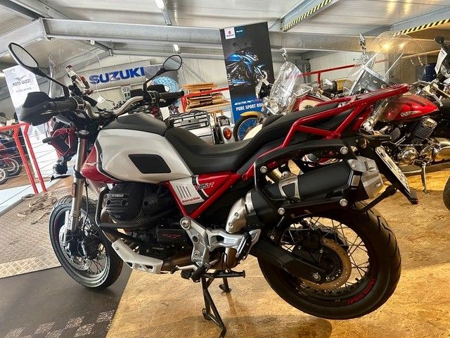 Ein rot-weißes Adventure-Motorrad ist in einem Ausstellungsraum ausgestellt, im Hintergrund sind weitere Motorräder zu sehen.
