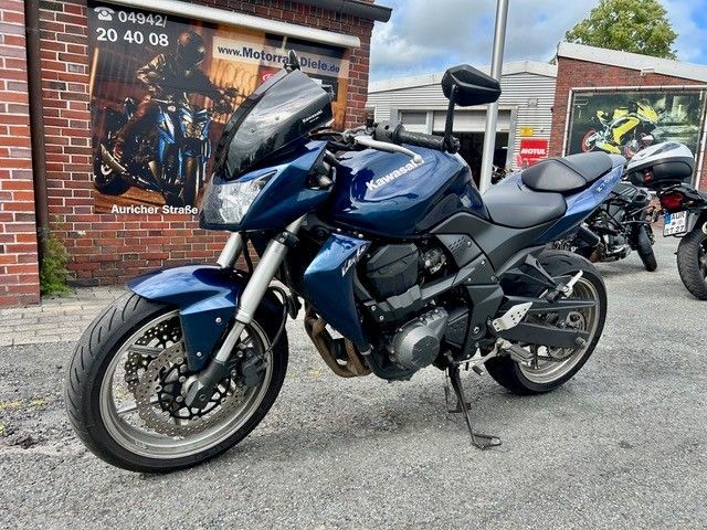 Ein blaues Tourenmotorrad parkte auf einer Straße vor einem Backsteingebäude und anderen Motorrädern.
