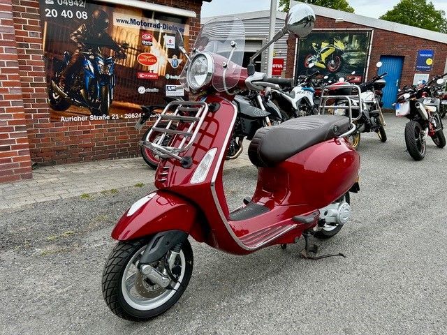 Ein roter Motorroller ist vor einem Backsteingebäude geparkt.