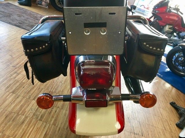 Ein rot-weißes Motorrad mit schwarzen Ledersatteltaschen