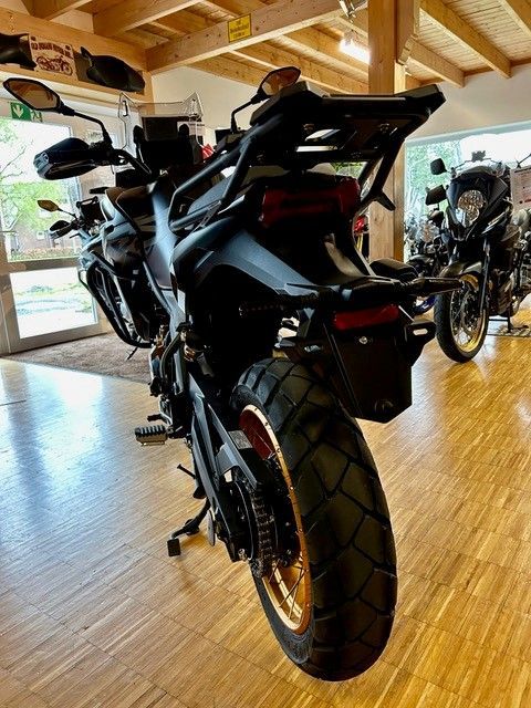 In einem Ausstellungsraum mit Holzboden ist ein Motorrad geparkt.