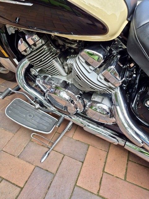 Verchromter Motorradmotor und Trittbrett parken auf einer gepflasterten Auffahrt.