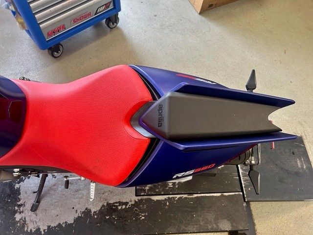 Draufsicht auf einen rot-blauen Motorradsitz und das Heckteil in einer Garage.