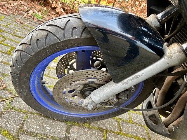 Eine Nahaufnahme des Vorderrads eines Motorrads auf einem gepflasterten Gehweg.