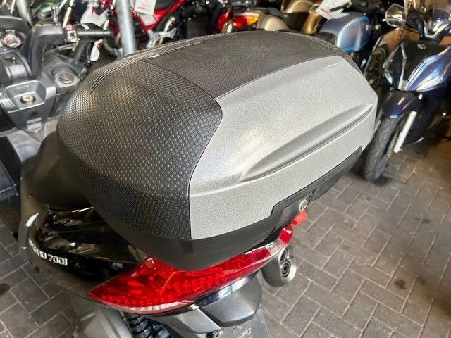 Graues und schwarzes Motorrad-Topcase, montiert auf einem roten Roller auf einem Parkplatz