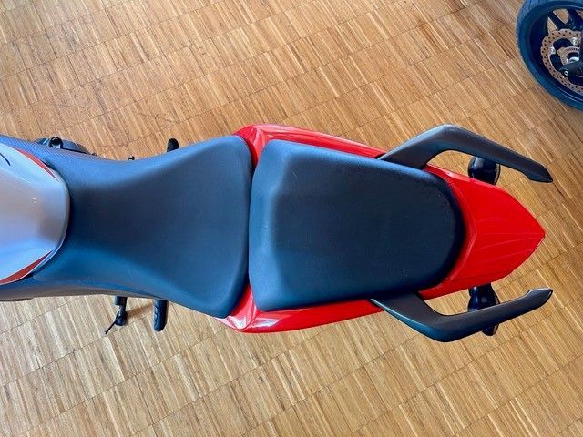Roter und schwarzer Motorradsitz, von oben auf einem Holzboden gesehen.