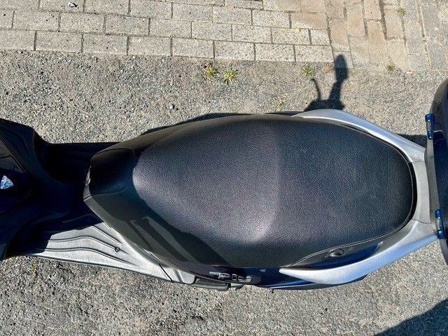 Ein schwarz-silberner Motorroller ist am Straßenrand geparkt.