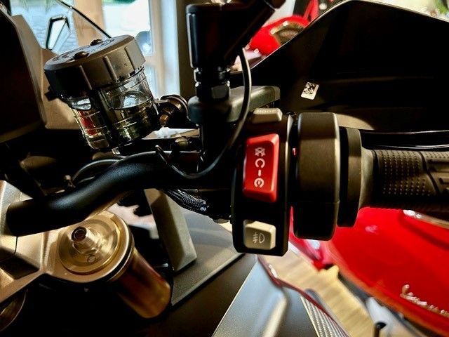 Eine Nahaufnahme eines Motorradlenkers mit einem roten Knopf, auf dem RC-E steht