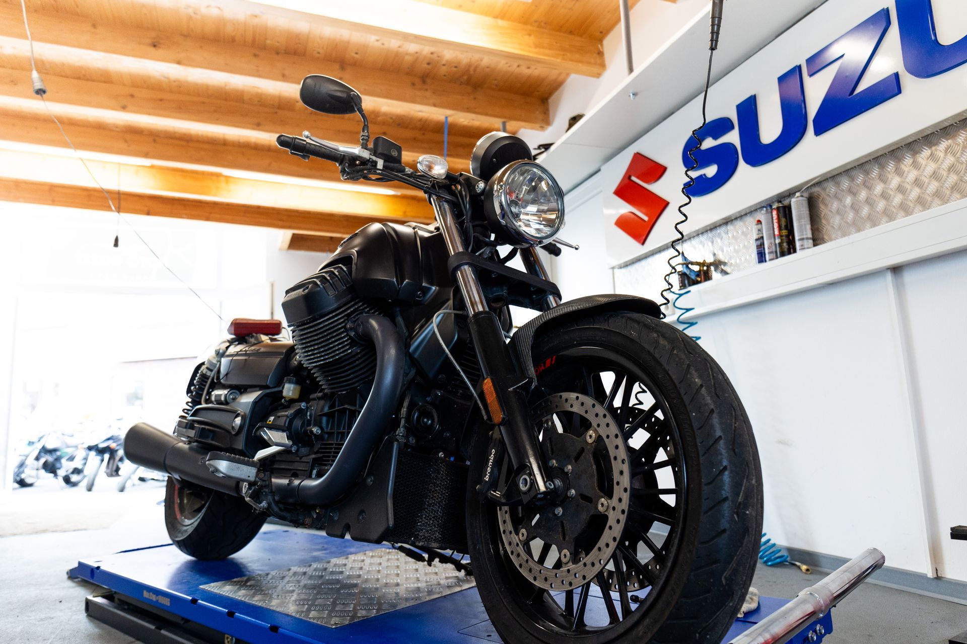 Ein schwarzes Motorrad steht auf einer Hebebühne in einer Garage.