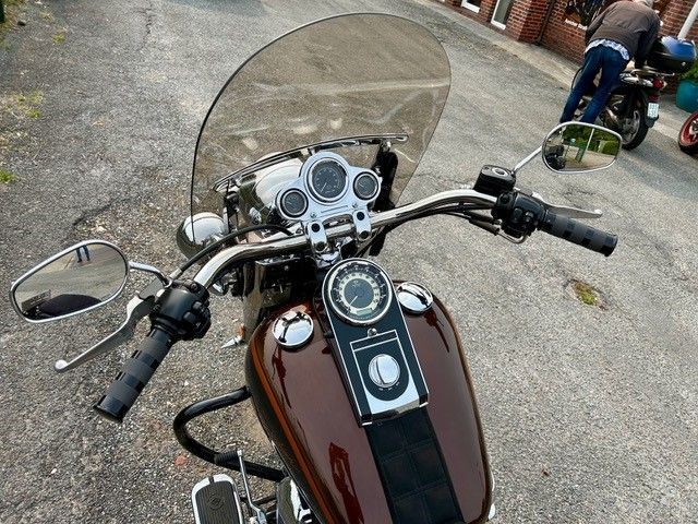 Ein braunes Motorrad mit Windschutzscheibe steht am Straßenrand.