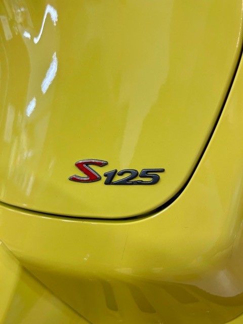Rotes „S125“-Emblem auf einem gelben Auto.