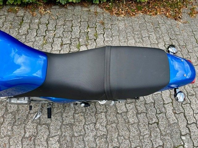 Blauer Motorradsitz auf einer strukturierten, grauen Steinoberfläche.