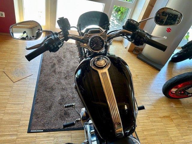 Schwarzes Motorrad im Innenbereich auf einem Teppich in der Nähe einer Tür, von oben betrachtet.