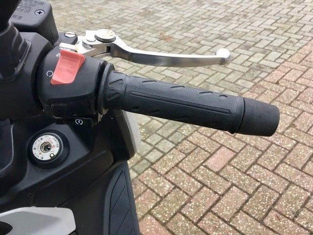 Eine Nahaufnahme des Lenkers eines Motorrads auf einem Ziegelpflaster.