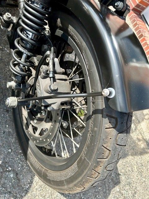 Schwarzer Hinterreifen, Rad und Kotflügel eines Motorrads; Nahaufnahme mit sichtbarer Aufhängung.