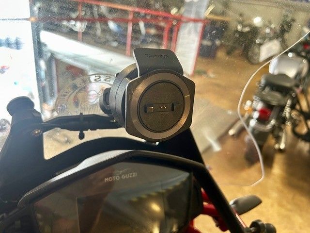 Schwarze Motorrad-Handyhalterung am Lenker hinter einer durchsichtigen Windschutzscheibe.