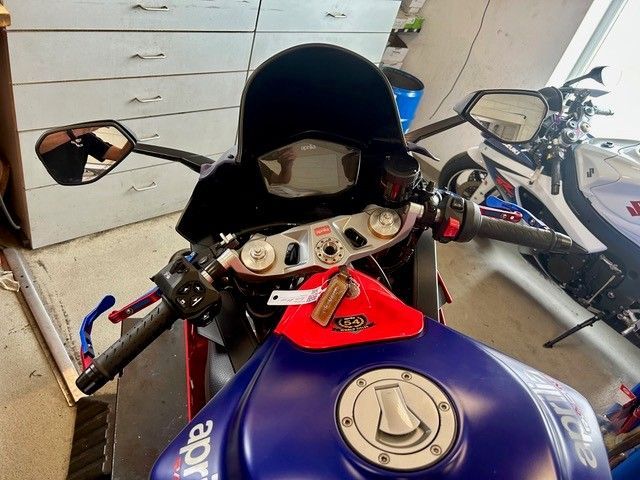 Blaues Sportmotorrad mit schwarzer Windschutzscheibe und Spiegeln, geparkt in einer Garage.