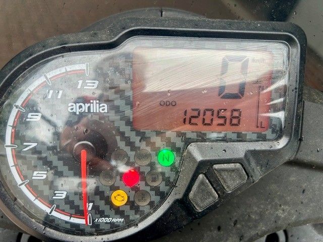 Aprilia Motorrad-Armaturenbrett mit digitaler Geschwindigkeitsanzeige 0 und Kilometerzähler 12058, Warnleuchten leuchten.