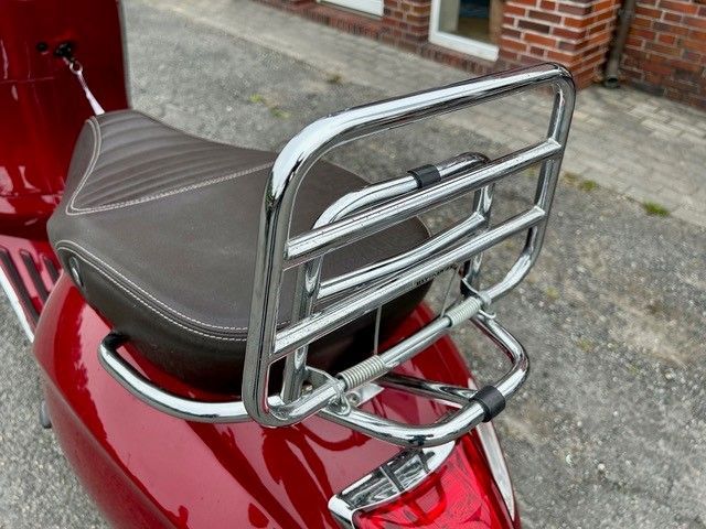 Ein roter Roller mit einem verchromten Gepäckträger auf der Rückseite