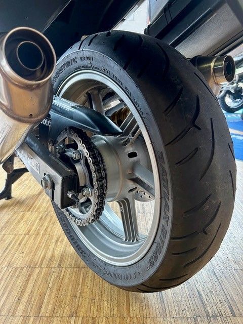 Hinterrad und Auspuffrohre eines Motorrads, Nahaufnahme auf einem Holzboden