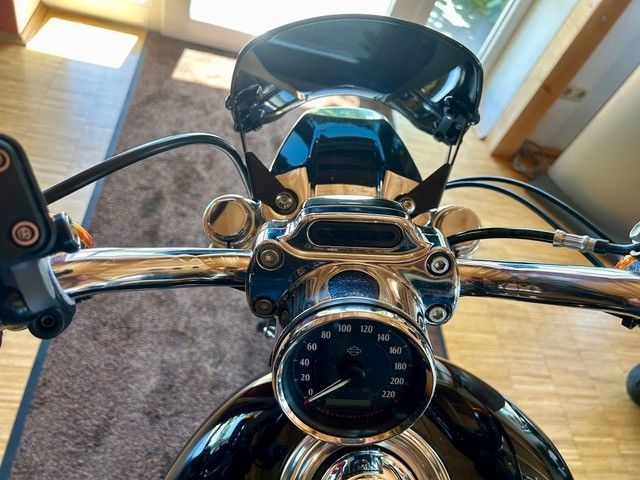 Verchromter Motorradlenker und Tachometer in einer Garage oder einem Eingangsbereich, im Hintergrund ein Fenster.