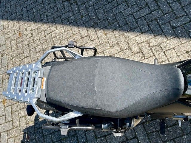 Draufsicht auf einen Motorradsitz und einen Gepäckträger auf einem Ziegelpflaster.