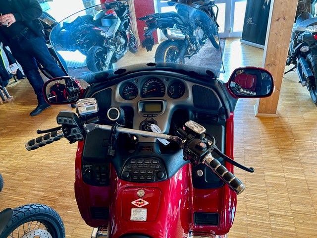 Rotes Motorrad-Armaturenbrett mit Anzeigen, Lenker und Spiegeln. Weitere Motorräder im Ausstellungsraum.