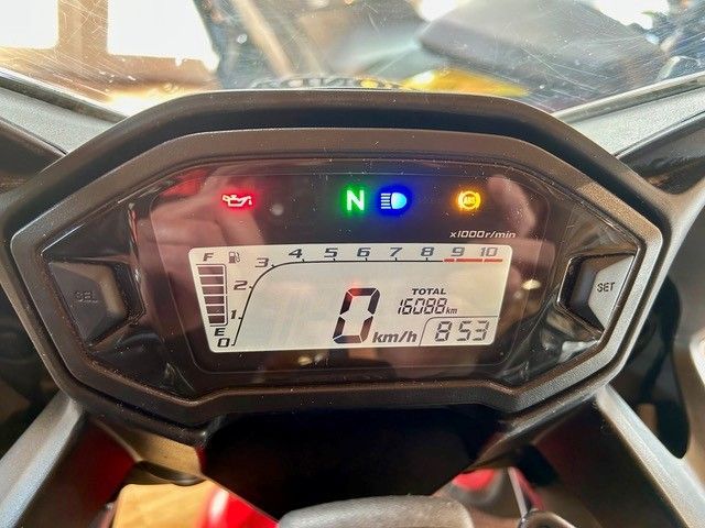 Das Motorrad-Armaturenbrett zeigt 0 km/h, Leerlauf und leuchtende Warnleuchten an.