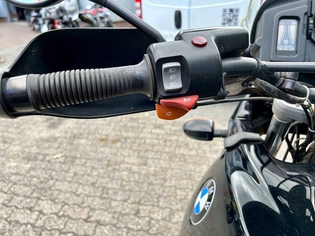 Motorradlenker mit Bedienelementen: Blinker, Warnblinkanlage und Startknopf; schwarz und silber.