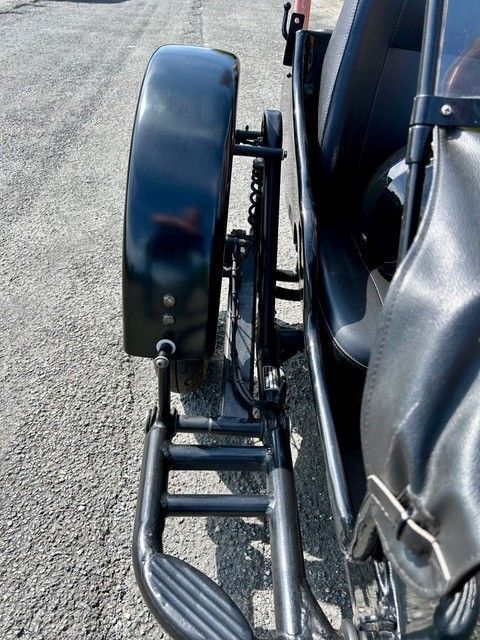 Seitenansicht eines schwarzen Motorradbeiwagens mit großem Reifen und Fußstütze.