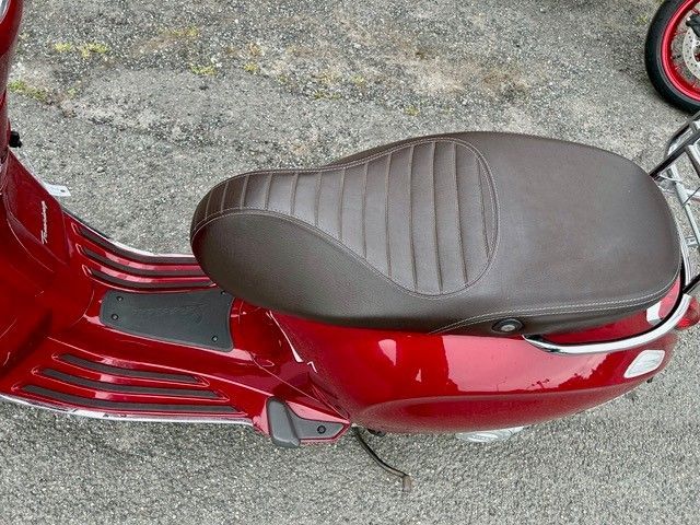 Auf dem Boden steht ein roter Motorroller mit braunem Sitz.
