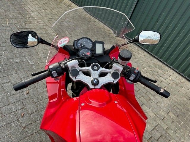 Ein rotes Motorrad ist auf einem gemauerten Bürgersteig geparkt