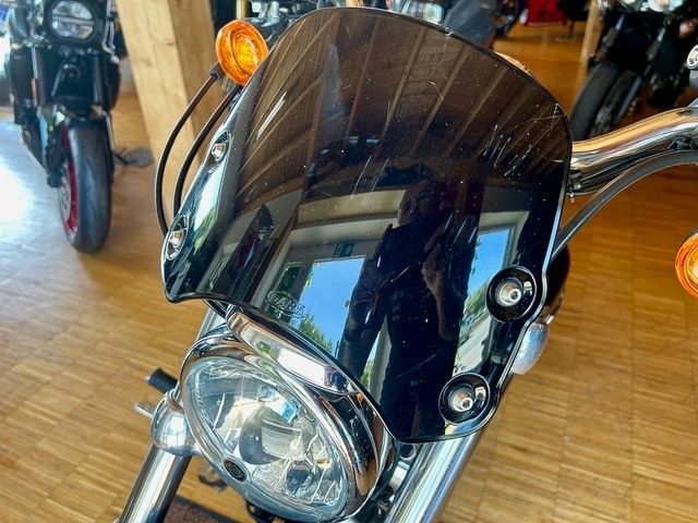 Vorderansicht eines Motorrads mit dunkler Windschutzscheibe und orangefarbenem Blinker in einem Innenraum