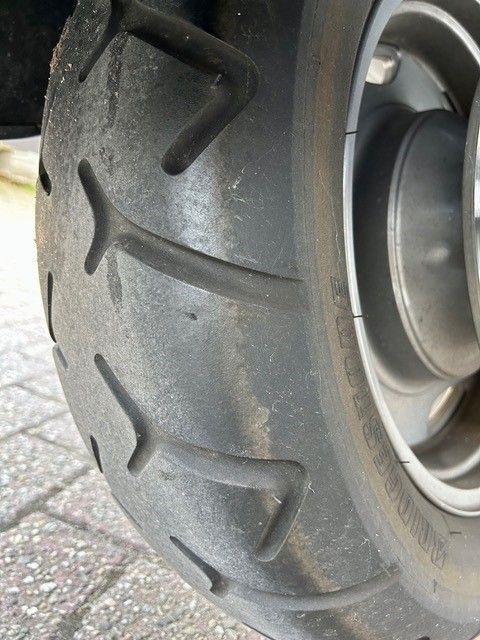 Eine Nahaufnahme eines Motorradreifens auf einer Ziegelsteinstraße.