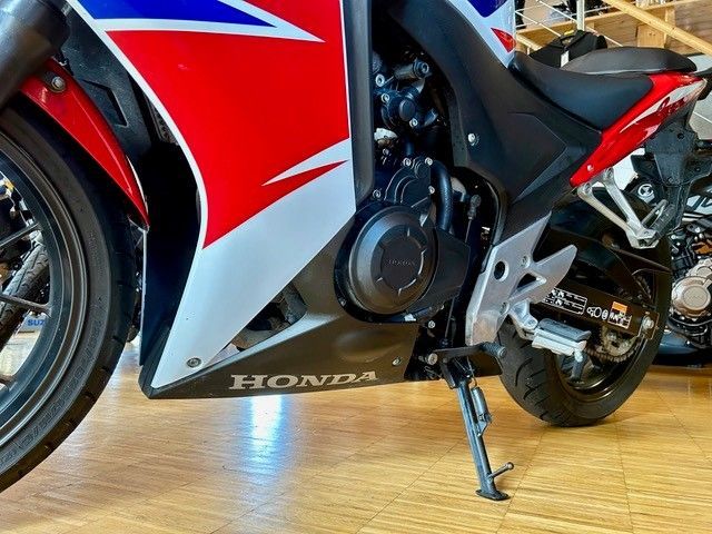 Nahaufnahme eines rot-weiß-blauen Honda-Motorrads auf dem Boden eines Ausstellungsraums.