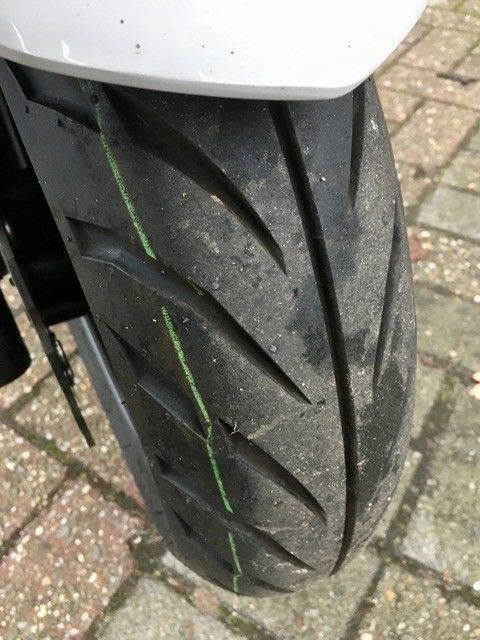 Eine Nahaufnahme eines Motorradreifens auf einem gepflasterten Gehweg.